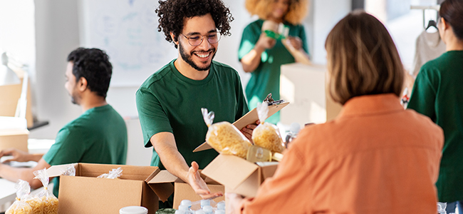happy volunteers packing food in donation boxes